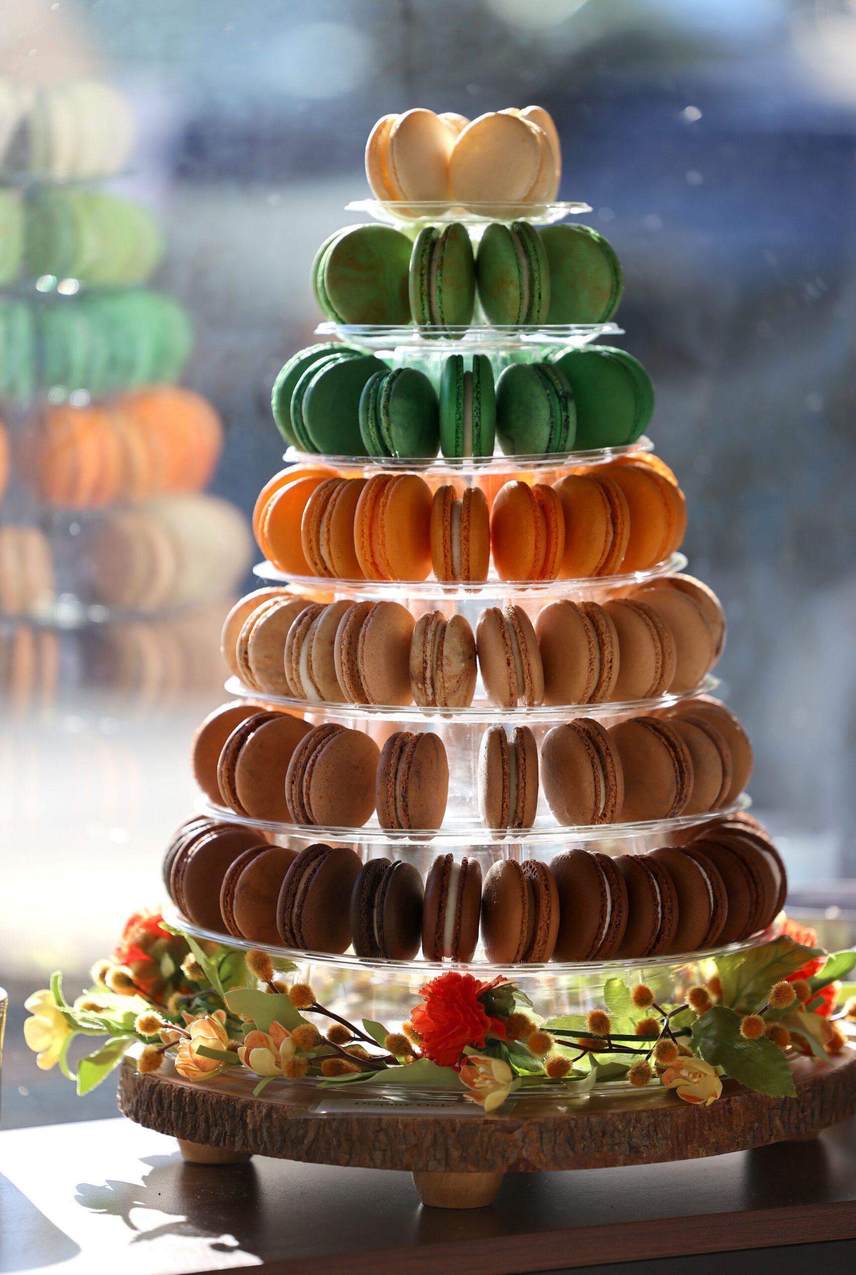 A tower of fall-themed flavors including pear ginger, apple pie, pumpkin spice, buttered rum, amaretto fig, and maple sits in the window at Madeleine's Macarons storefront in Yountville, Sunday, Sept. 10, 2023. (Beth Schlanker / The Press Democrat)