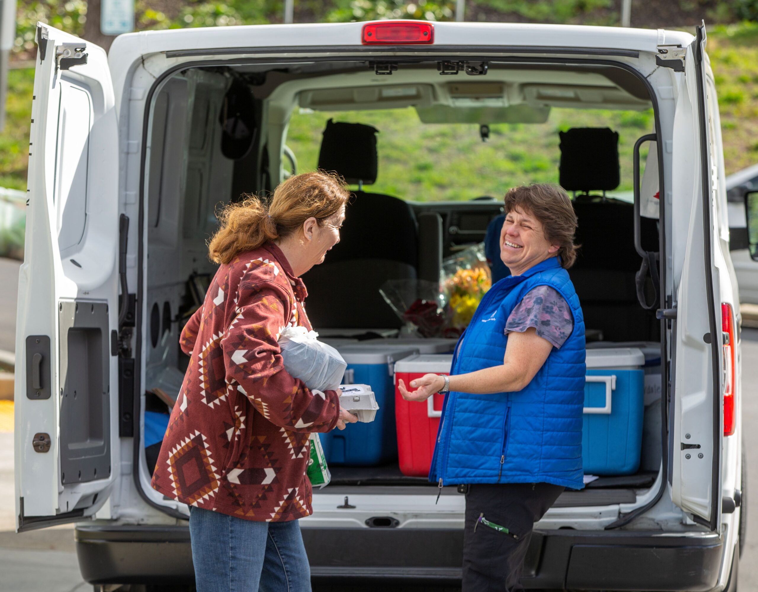 Longtime Council on Aging Meals on Wheels driver and Fleet Manager Shannon Holck smiles after handing off a meal at the Drive Up/Pick Up site in front of the senior center at King's Valley Senior Apartments in Cloverdale, February 21, 2023. (Chad Surmick / The Press Democrat)