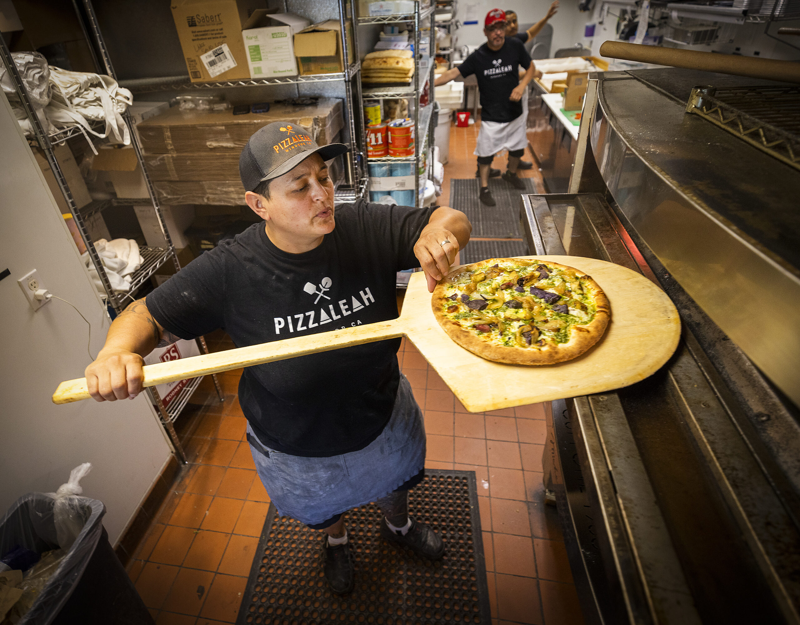 Leah Scurto, owner of PizzaLeah, checks to see if a pizza crust its crisp enough to serve at her Windsor restaurant. (John Burgess/The Press Democrat)