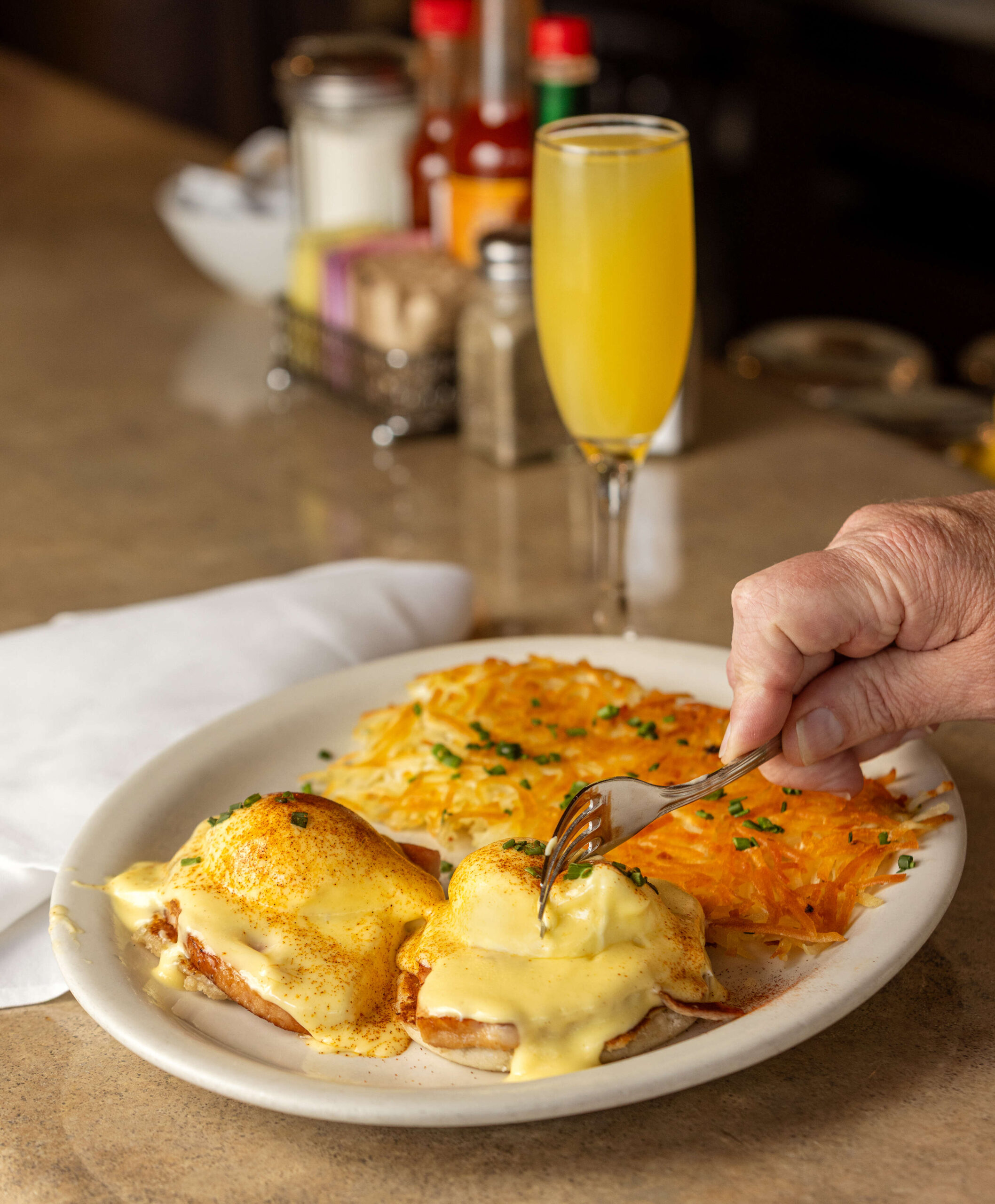 Eggs Benedict with two poached eggs, Caggiano’s ham on an english muffin topped with a Champagne hollandaise, hash browns and a Mimosa from Jeffrey’s Hillside Cafe Thursday, May 22, 2025 in Santa Rosa. (John Burgess / The Press Democrat)