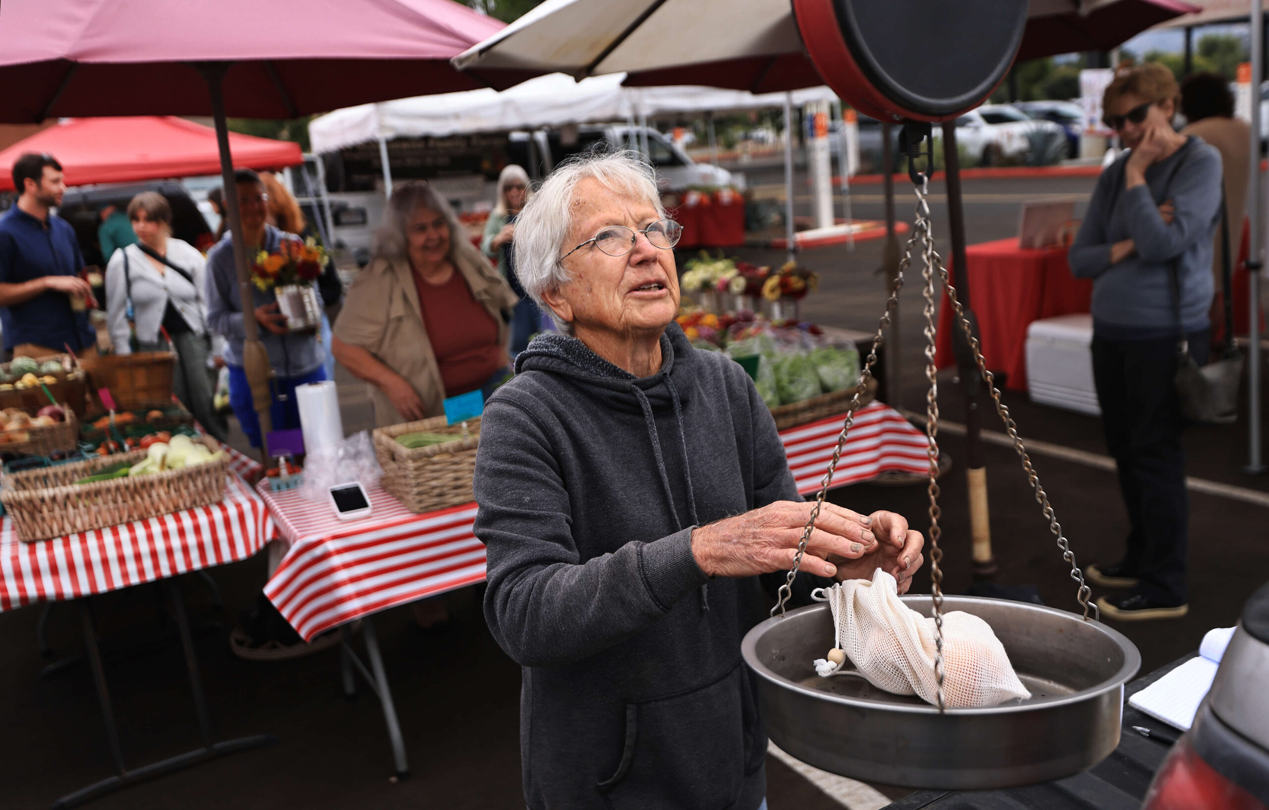 Renee Kiff, 83, of Ridgeview Farm in Alexander Valley, weighs peaches from her farm during the Santa Rosa Certified Farmers Market at the Luther Burbank Center for the Arts in Santa Rosa, Wednesday, Aug. 2, 2023. (Kent Porter / The Press Democrat)