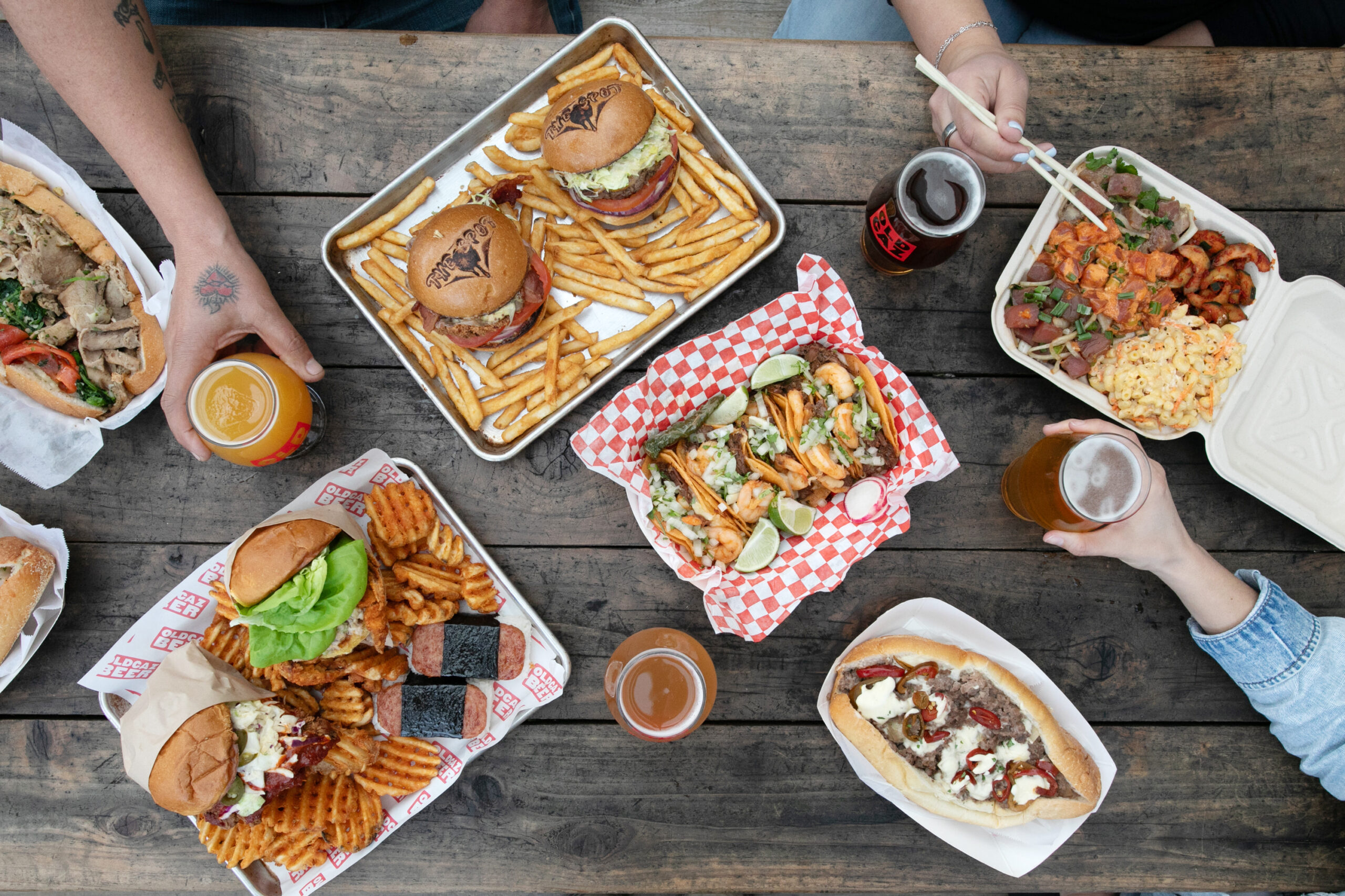 A selection of food from pop-up vendors at Old Caz Beer in Rohnert Park. Clockwise from top left, Mamadios' Italian roast pork sandwich; burgers and fries from The Spot food truck; Hawaiian plate lunch from The Poke Truck; Philly cheesesteak from Mamadios; tacos from Galvan's; fried chicken sandwich, fried soft shell crab sandwich, Spam musubi and waffle fries from Shokakko. (Eileen Roche)