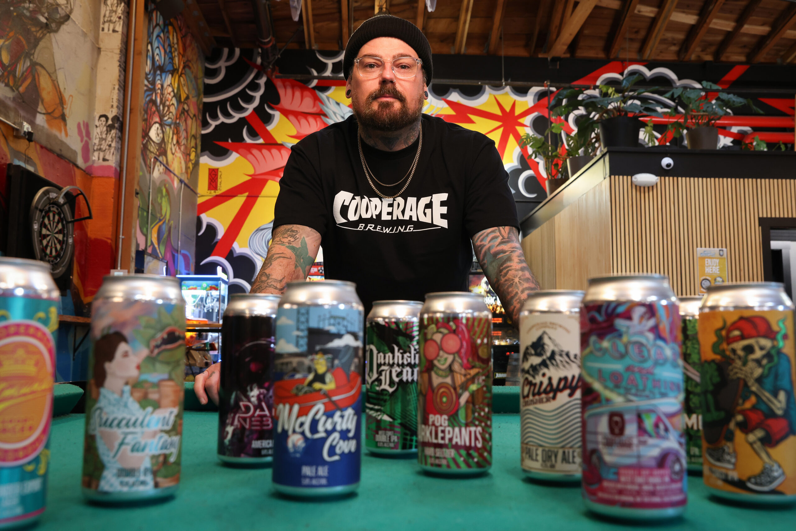 Cooperage Brewing Company art director and head of design Nicky London with the numerous beer cans featuring his artwork in Santa Rosa on Tuesday, February 3, 2026. (Christopher Chung/The Press Democrat)