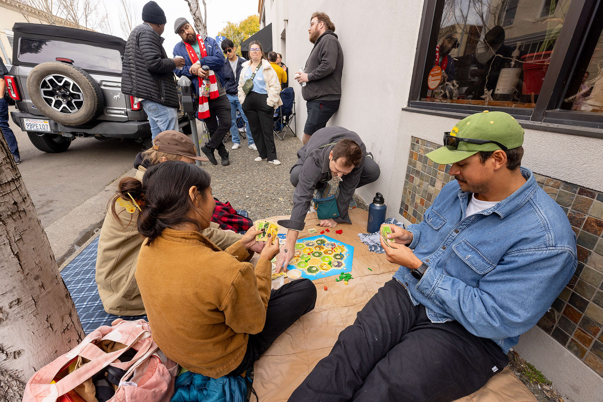Friends play a board game while waiting in line Friday morning March 21, 2025 for the release of Pliny the Younger triple IPA from the Russian River Brewing Co. in downtown Santa Rosa. 