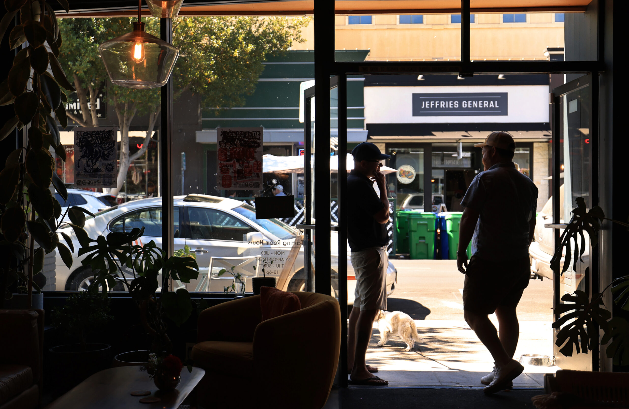 Ben Brenner, right, the founding partner of Benevolent Neglect Wines, talks with a friend at the front of the one-room tasting location among Napa’s downtown storefront restaurant and tasting room businesses, Friday, July 24, 2026. (Kent Porter / The Press Democrat)