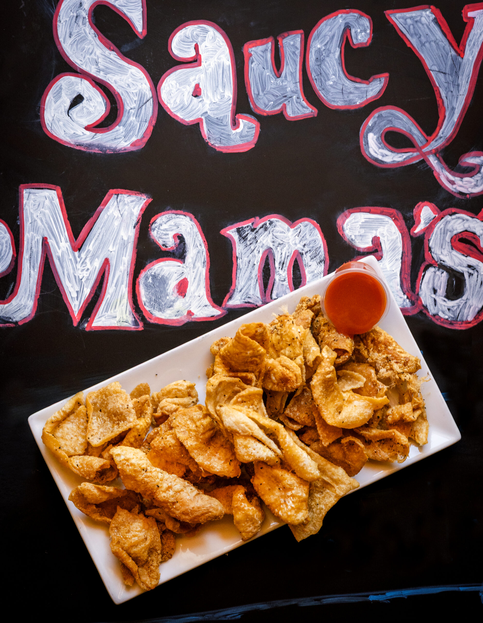 Cracklin' Chicken seasoned, deep fried to a crisp and served with a side of hot sauce from Saucy Mama’s Jook Joint 
