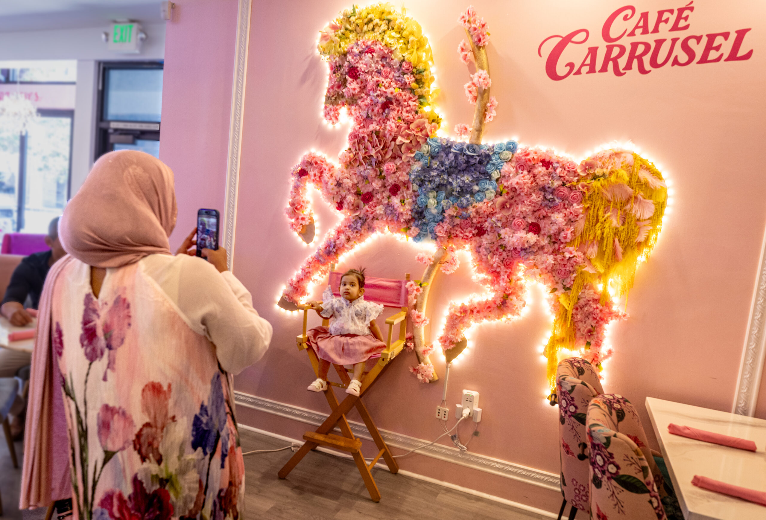 Sumiya Ahmed, of Santa Rosa and Dubai, takes a photo of her daughter Issa, 1, in front of the glowing flower horse at Café Carrusel Tuesday, July 28, 2026 in Santa Rosa. (John Burgess/The Press Democrat)