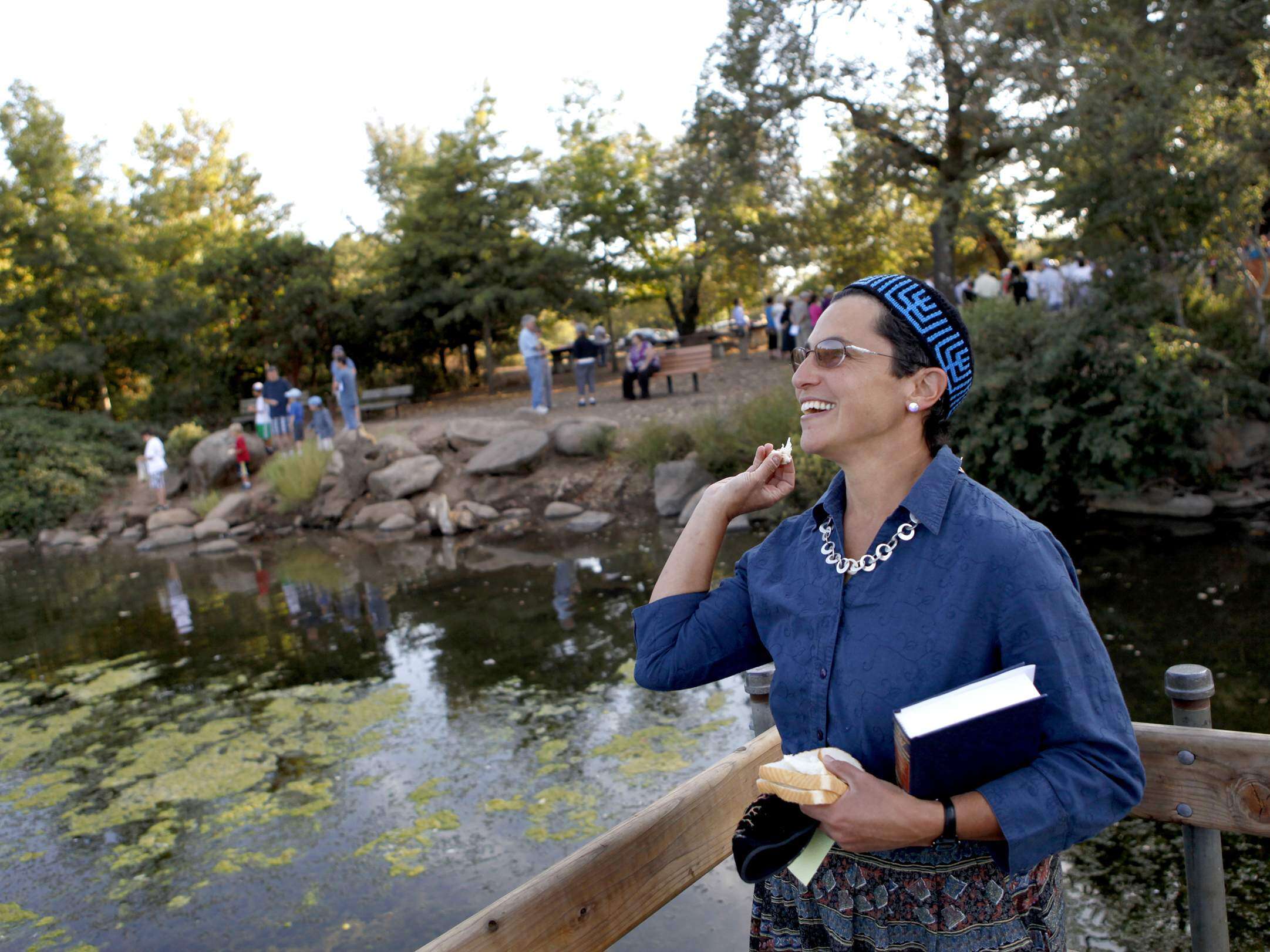 Joslyn Metzger throws bread into Lake Ralphine as a representation of casting away sin during a Rosh Hashanah Tashlich Service